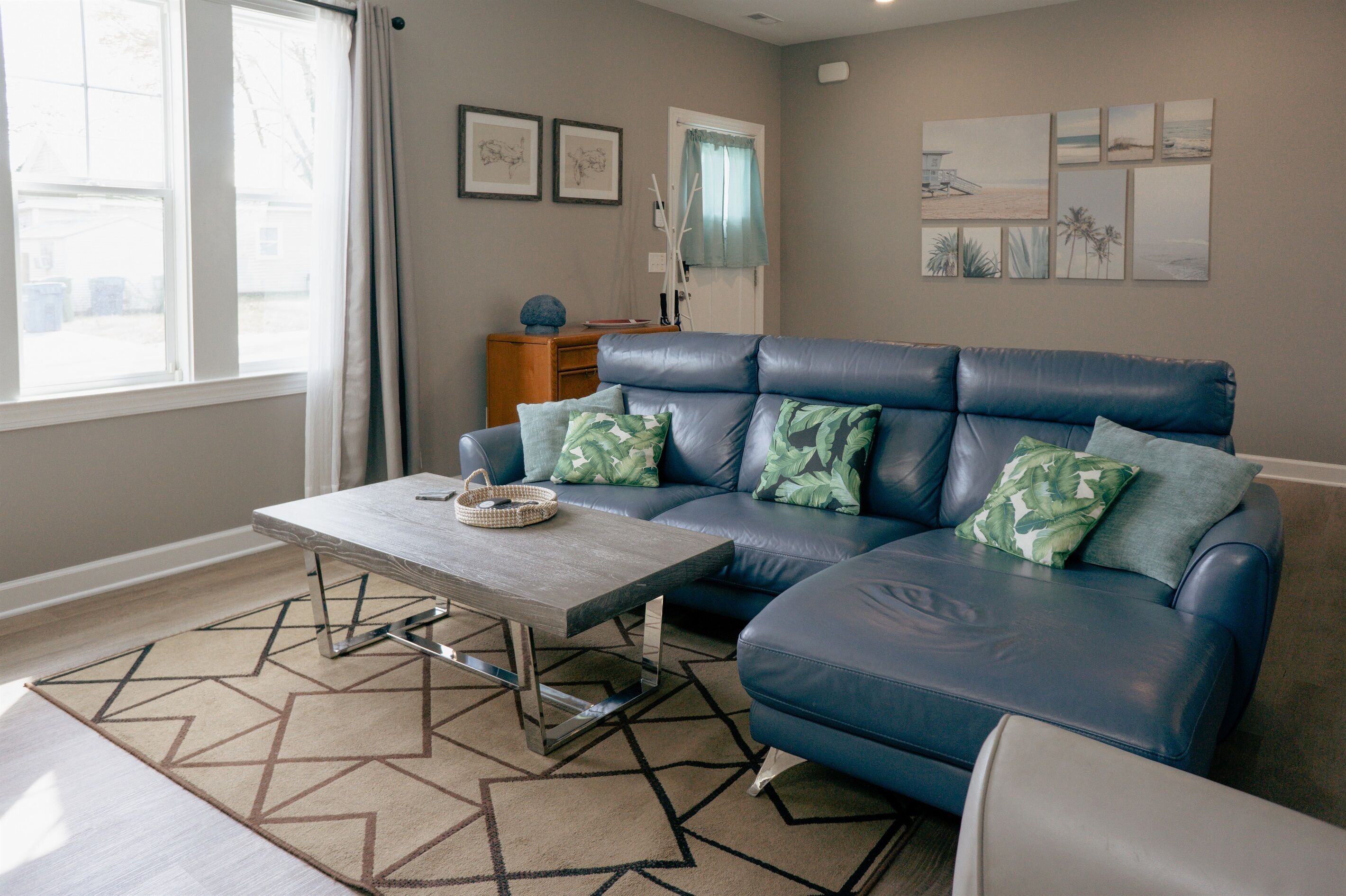 A living room with a blue leather sofa, a wooden coffee table, and a patterned rug.