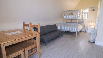 Et værelse med et træbord, en grå sofa og en køjeseng.