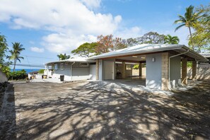 A residential property with a covered porch, a garage, and a view of the ocean. - 🌴Hale Honu | AC | Ocean Views | Renovated Master | A Diver's Paradise Awaits🌴 (Kailua Kona)