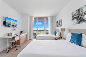 Ein Hotelzimmer mit Bett, Schreibtisch, Stuhl und einem großen Fenster mit Blick auf die Stadt.