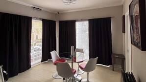 A room with a round glass table, four white chairs with red cushions, a ceiling fan, and a window with black curtains. - Pleasant 2-bedroom apartment with AC in Beverly Hills Near Rodeo Dr. (Beverly Hills)