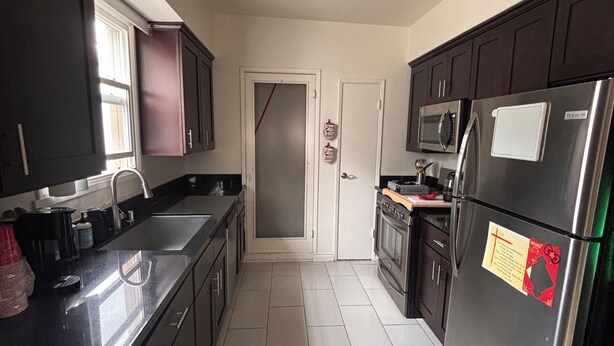 A kitchen with dark cabinets, a stainless steel refrigerator, a microwave, and a tiled floor. - Pleasant 2-bedroom apartment with AC in Beverly Hills Near Rodeo Dr. (Beverly Hills)