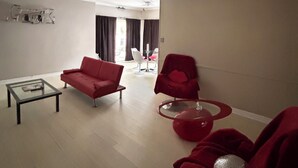 A living room with a sofa, armchair, coffee table, and a red chair. - Pleasant 2-bedroom apartment with AC in Beverly Hills Near Rodeo Dr. (Beverly Hills)