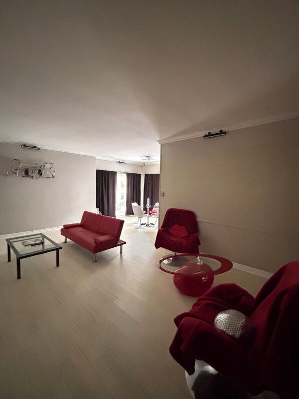 Ein Wohnzimmer mit einer Couch, einem Sessel, einem Couchtisch und einem roten Stuhl.