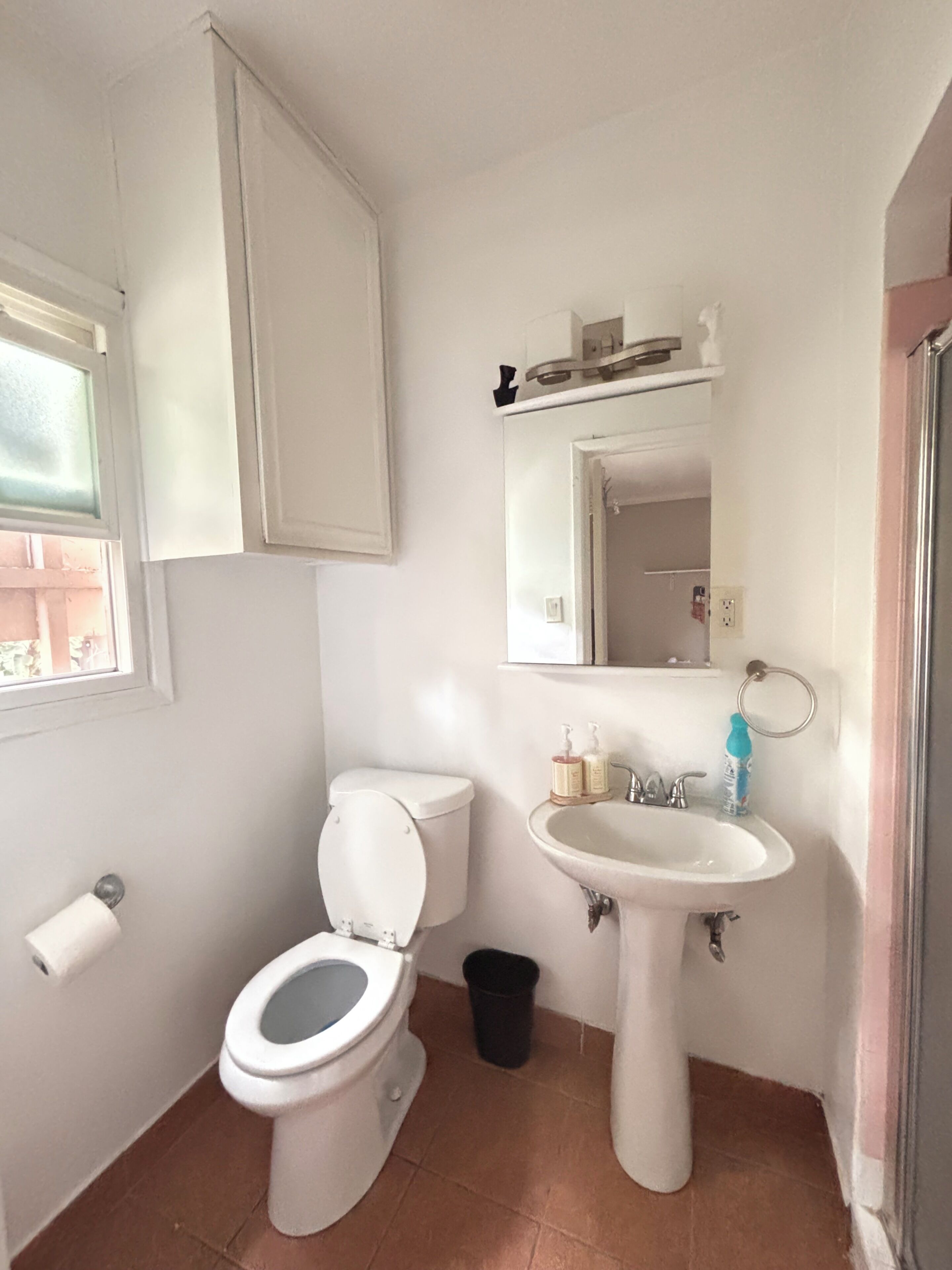 Un baño con inodoro, lavamanos y espejo.