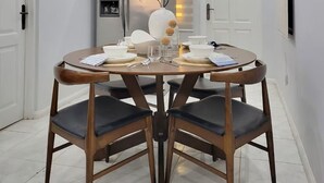 A dining area with a round table, four chairs, a refrigerator, and a door with a light fixture. - Cozy Duafe Villa/WI-FI/ 24hr Security/10mins to Airport (Adenta Municipality)