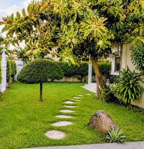 A well-maintained garden with a lawn, a neatly trimmed bush, and a stone pathway. - Cozy Duafe Villa/WI-FI/ 24hr Security/10mins to Airport (Adenta Municipality)