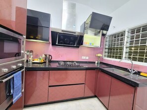 A kitchen with stainless steel appliances, a gas stove, a microwave, and a window with bars.