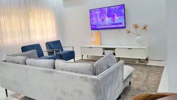 A modern living room with a sofa, a television, and a white console table. - Cozy Duafe Villa/WI-FI/ 24hr Security/10mins to Airport (Adenta Municipality)