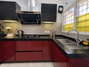 A modern kitchen with a gas stove, stainless steel appliances, and red cabinetry. - Cozy Duafe Villa/WI-FI/ 24hr Security/10mins to Airport (Adenta Municipality)