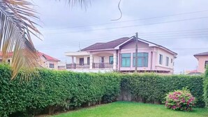 A residential area with a well-maintained lawn, a hedge, and a house with a balcony. - Cozy Duafe Villa/WI-FI/ 24hr Security/10mins to Airport (Adenta Municipality)