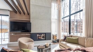 Ein modernes Wohnzimmer mit Kamin, Sofa, Sesseln und Fernseher.