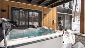 Ein Whirlpool vor einem Holzbau mit Blick auf eine verschneite Landschaft.