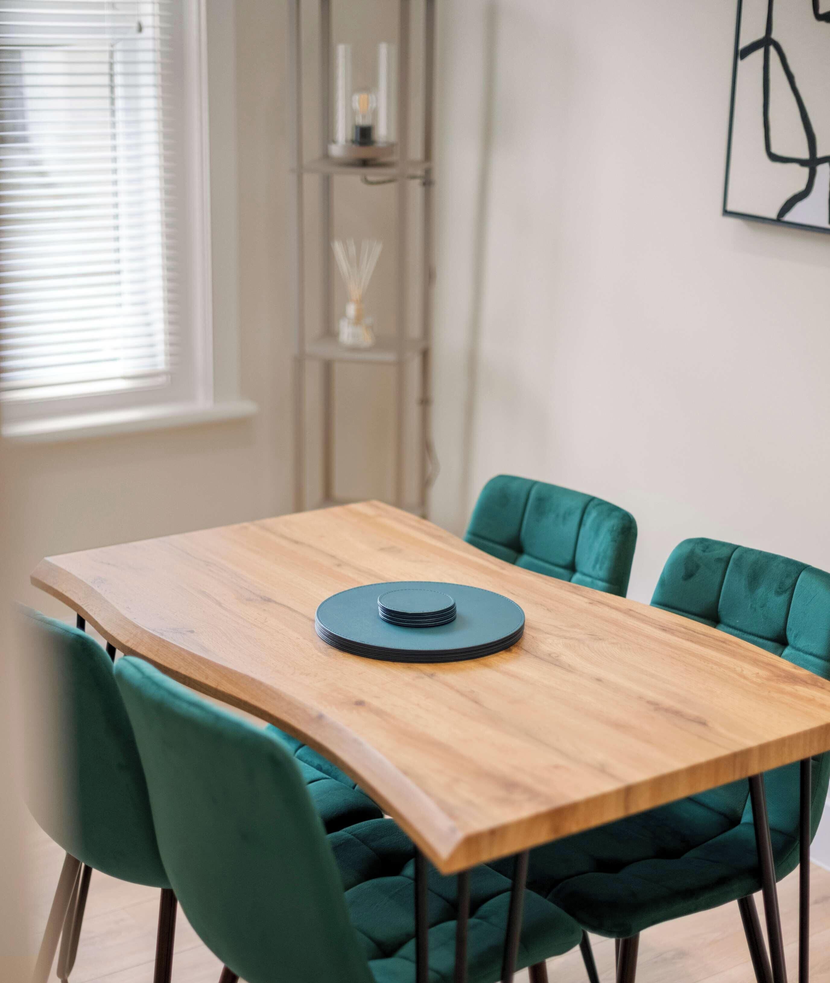 A dining table with a wooden top and four teal chairs.