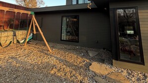 Una casa moderna amb un cadireta, un camí de pedra i una finestra gran.
