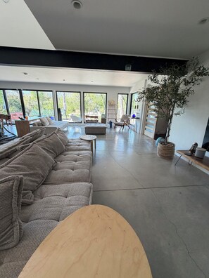 A spacious living area with a large sofa, a coffee table, and a potted plant. - Cottonwood Retreat, a unique luxury and urban Farm experience (Dallas)