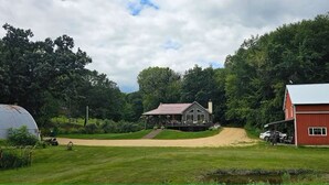 A rural property with a large barn, a house with a porch, and a covered structure.