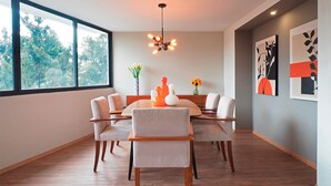 A modern dining room with a wooden table and chairs, a hanging light fixture, and framed artwork on the wall. - Polanco Family Terrace By The Local Way (Mexico City)