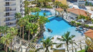 Ein Resort mit einem zentralen Pool, mehreren Gebäuden und Palmen.