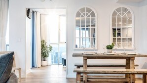 Ein Zimmer mit einer hölzernen Bank, einem Esstisch mit Weingläsern und Blick durch ein Fenster.