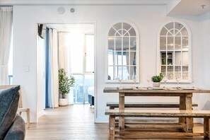 Ein Zimmer mit einer hölzernen Bank, einem Esstisch mit Weingläsern und Blick durch ein Fenster.