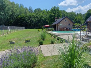 A backyard with a swimming pool, a brick house, and a fenced area.