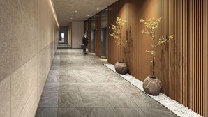 A corridor with a polished stone floor, wooden panel walls, and two large vases with plants. - Daiwa Roynet Hotel Matsue-ekimae (Matsue)