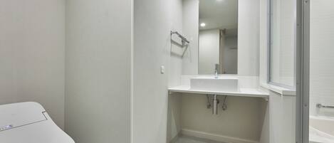 A modern bathroom with a toilet, sink, and mirror.