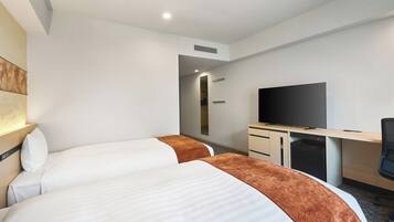 Ein Hotelzimmer mit zwei Betten, einem Schreibtisch, einem Flachbildfernseher und einem begehbaren Kleiderschrank.