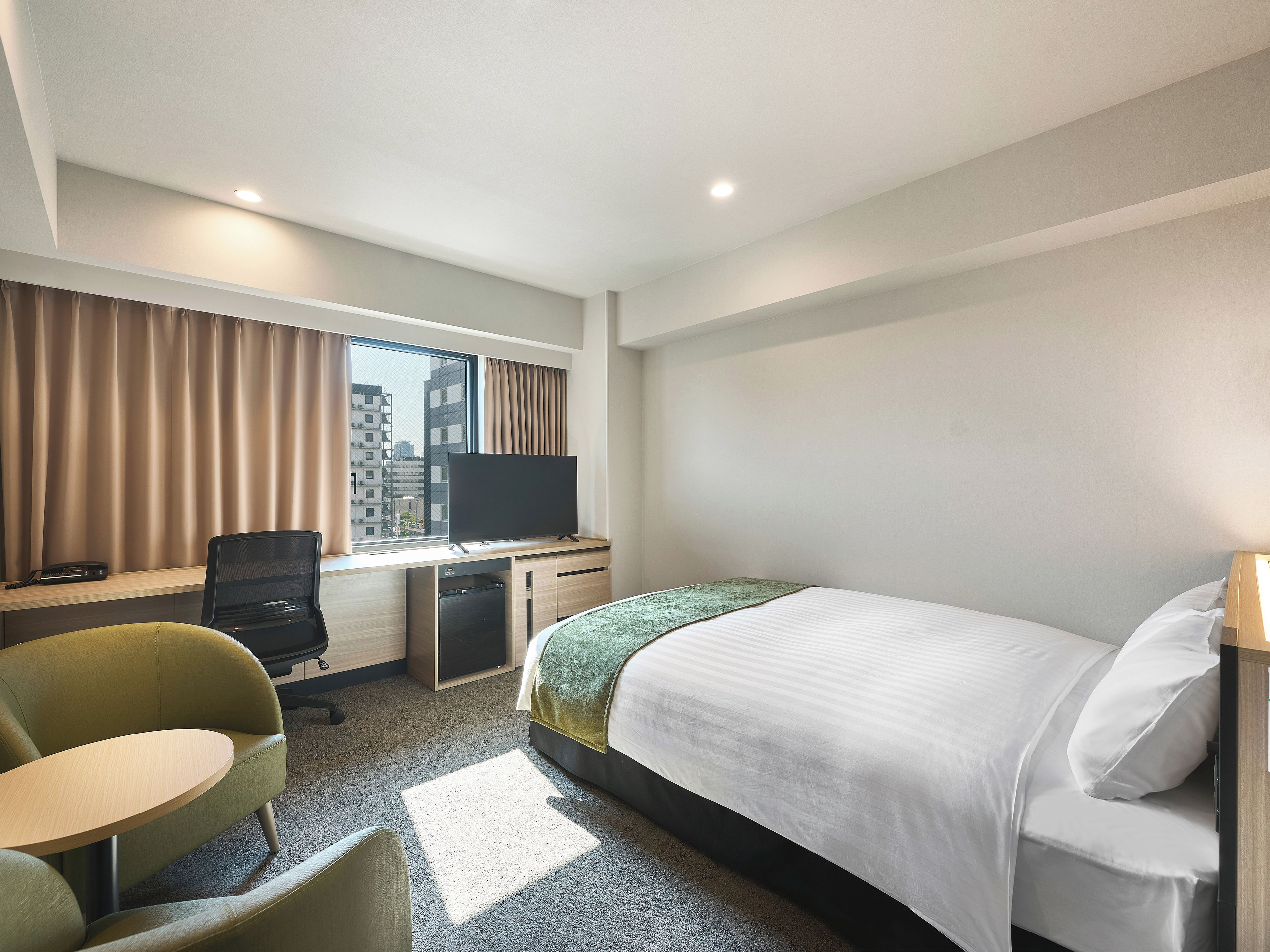 Une chambre d’hôtel équipée d’un lit, d’un bureau, d’une chaise, d’une télévision et d’une fenêtre avec des rideaux.