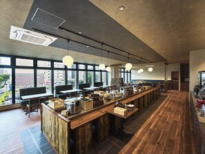 Un café moderno con una barra alargada, zona de estar y amplios ventanales con vistas a la ciudad.