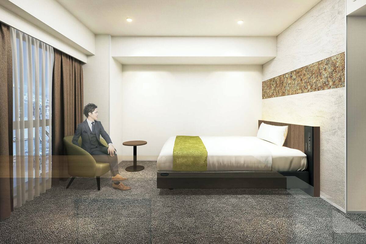 A hotel room with a bed, a chair, a small table, and a view through the window.