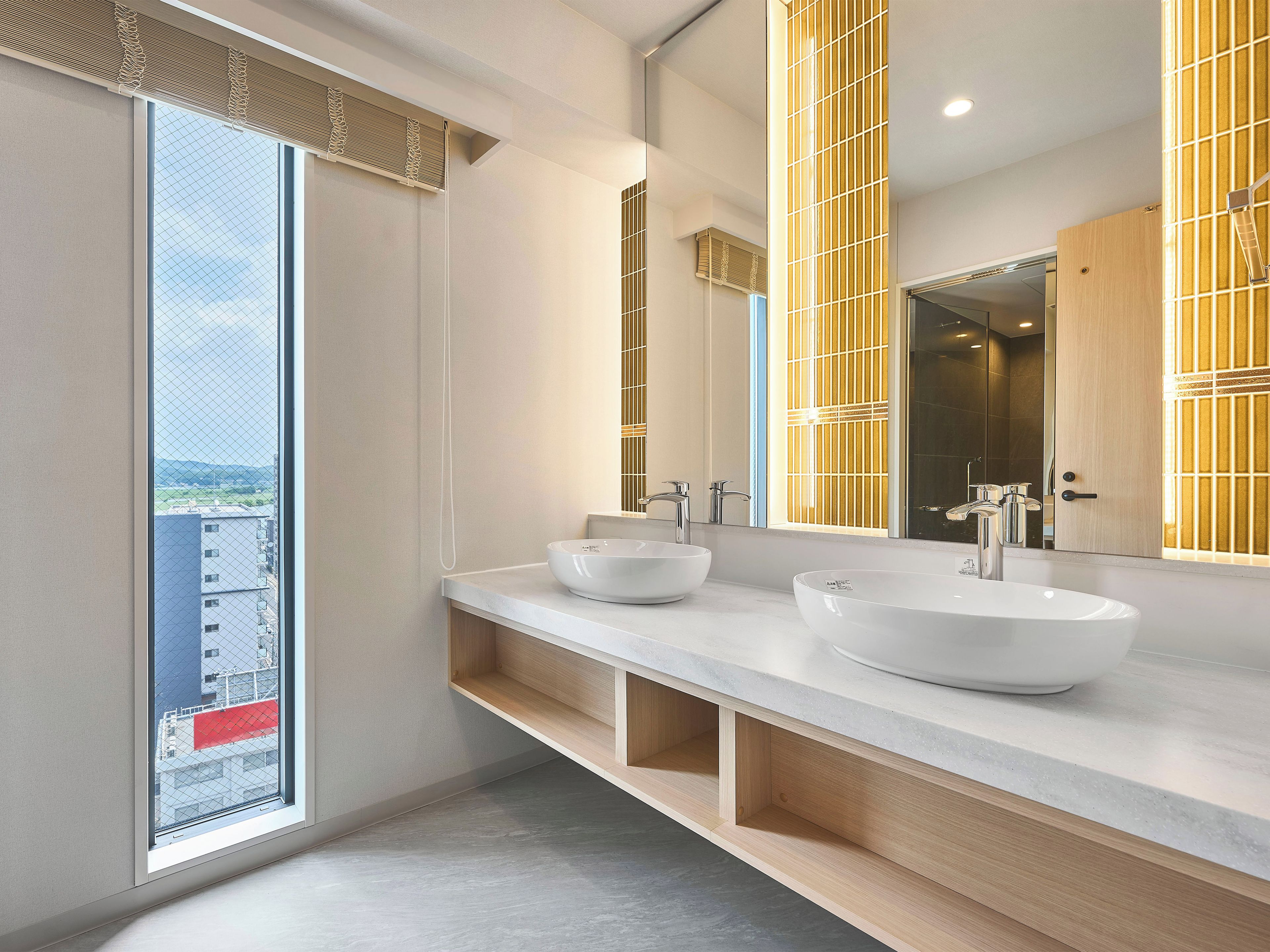 Un baño moderno con un ventanal amplio, dos lavamanos y un espejo.