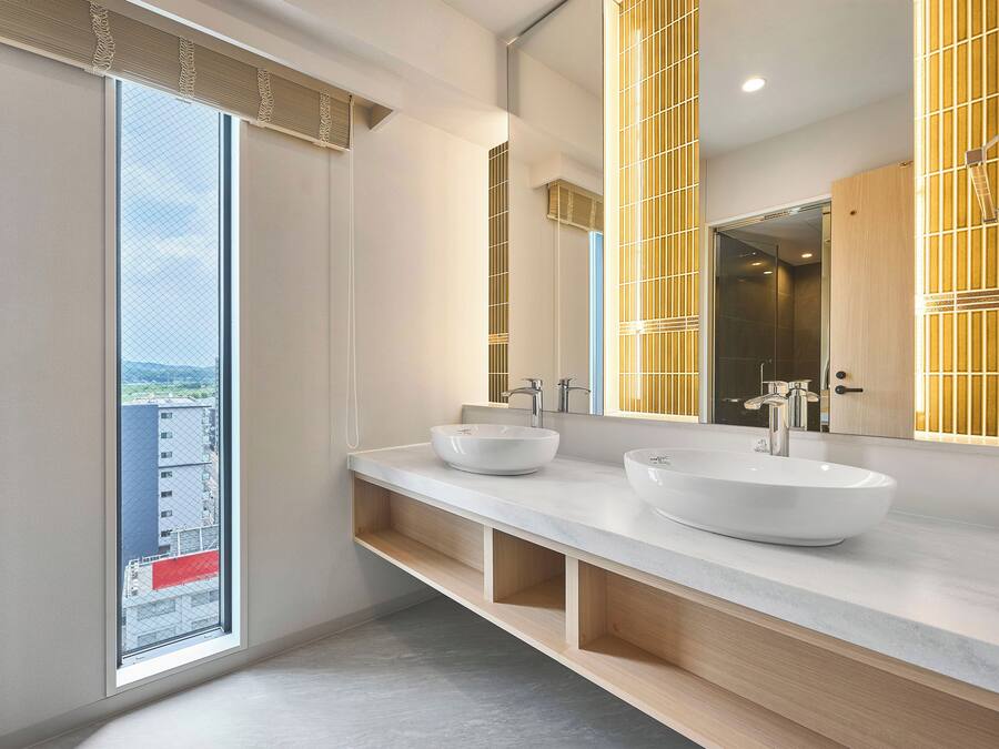Un baño moderno con un ventanal amplio, dos lavamanos y un espejo.