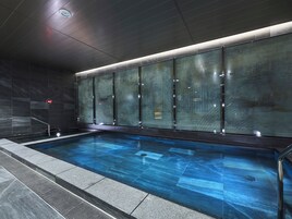 Una piscina interior moderna con paredes de vidrio y un reloj digital.