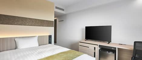 Habitación de hotel moderna con una cama grande, un televisor de pantalla plana, un escritorio con computadora y un lavavajillas compacto.