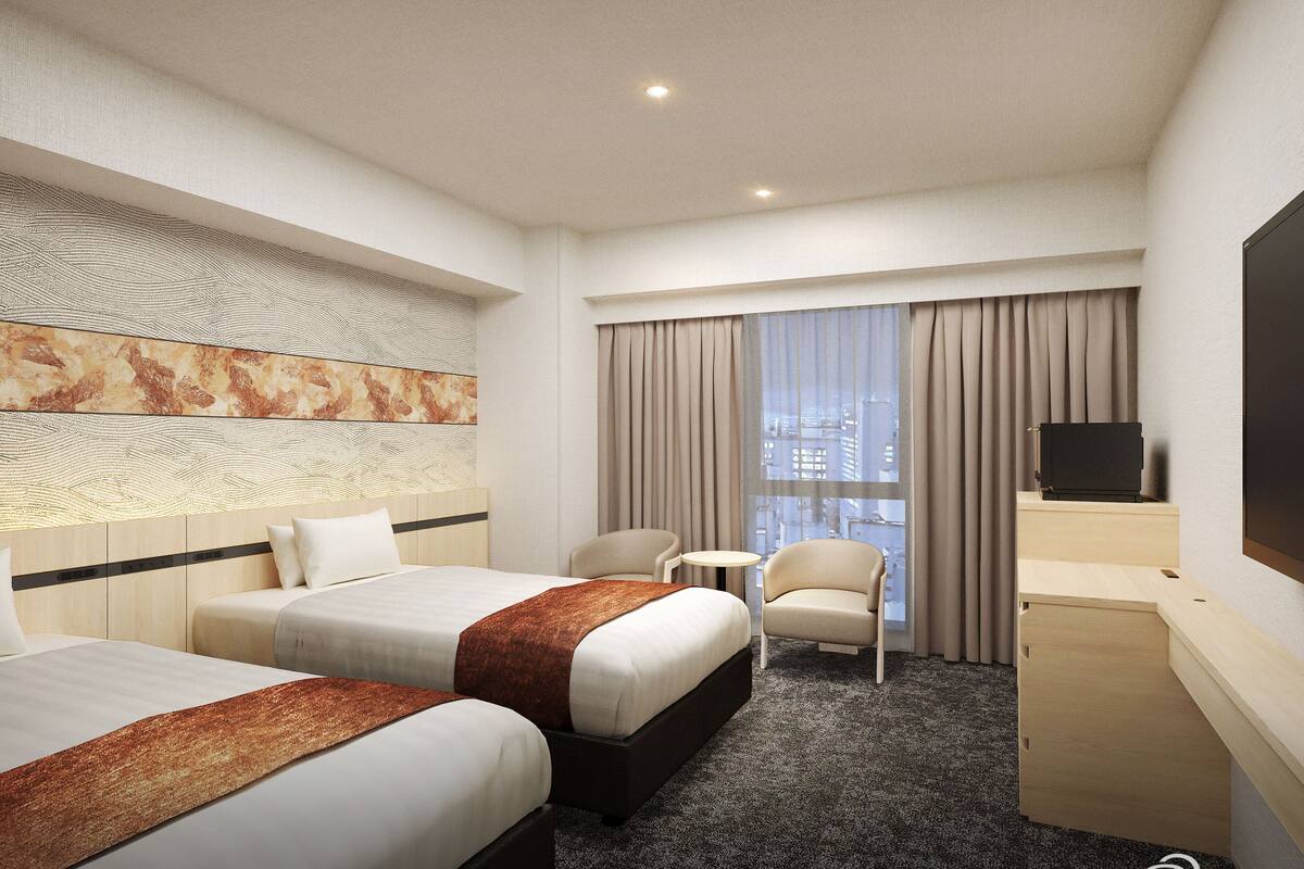 A hotel room with two beds, a desk, a chair, a small table, and a TV.