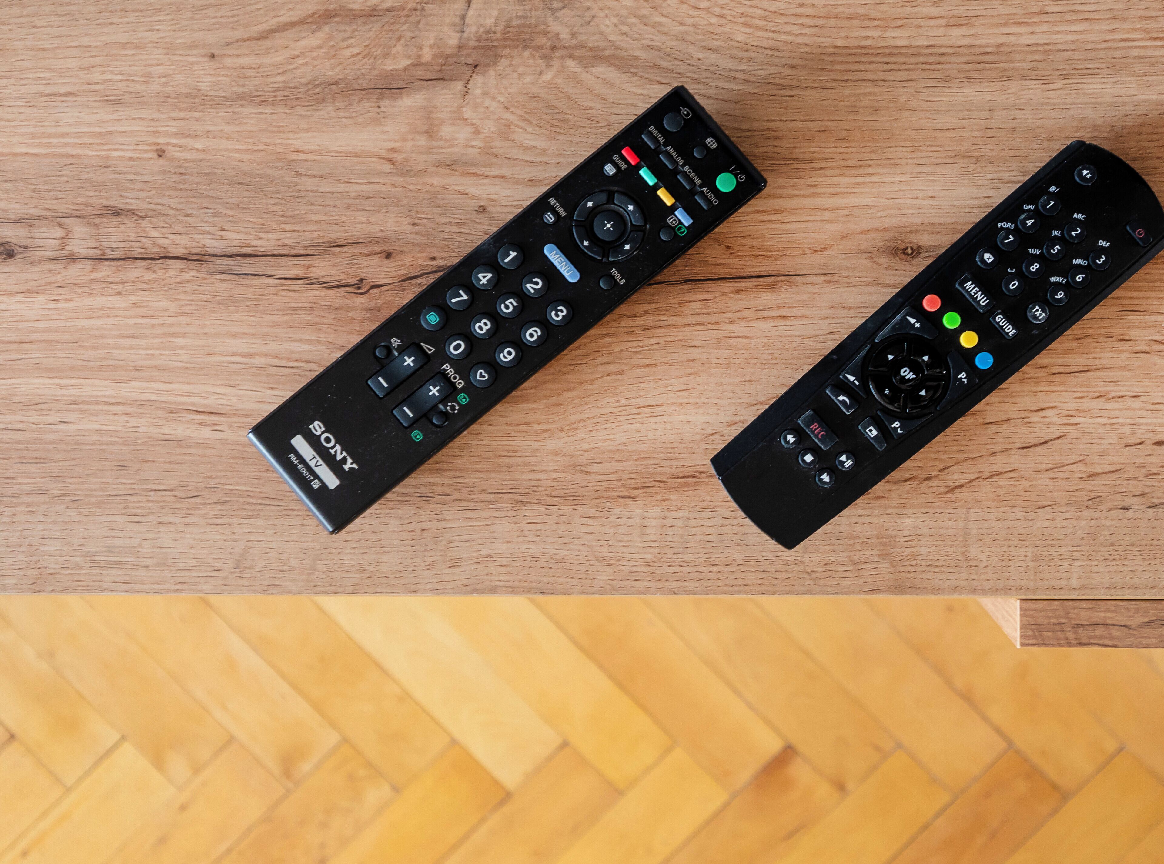 Dos controles remotos negros sobre una superficie de madera.