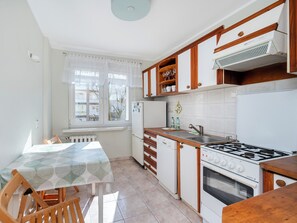 Une cuisine de taille réduite comprenant une table à manger, des chaises, une cuisinière et un réfrigérateur.
