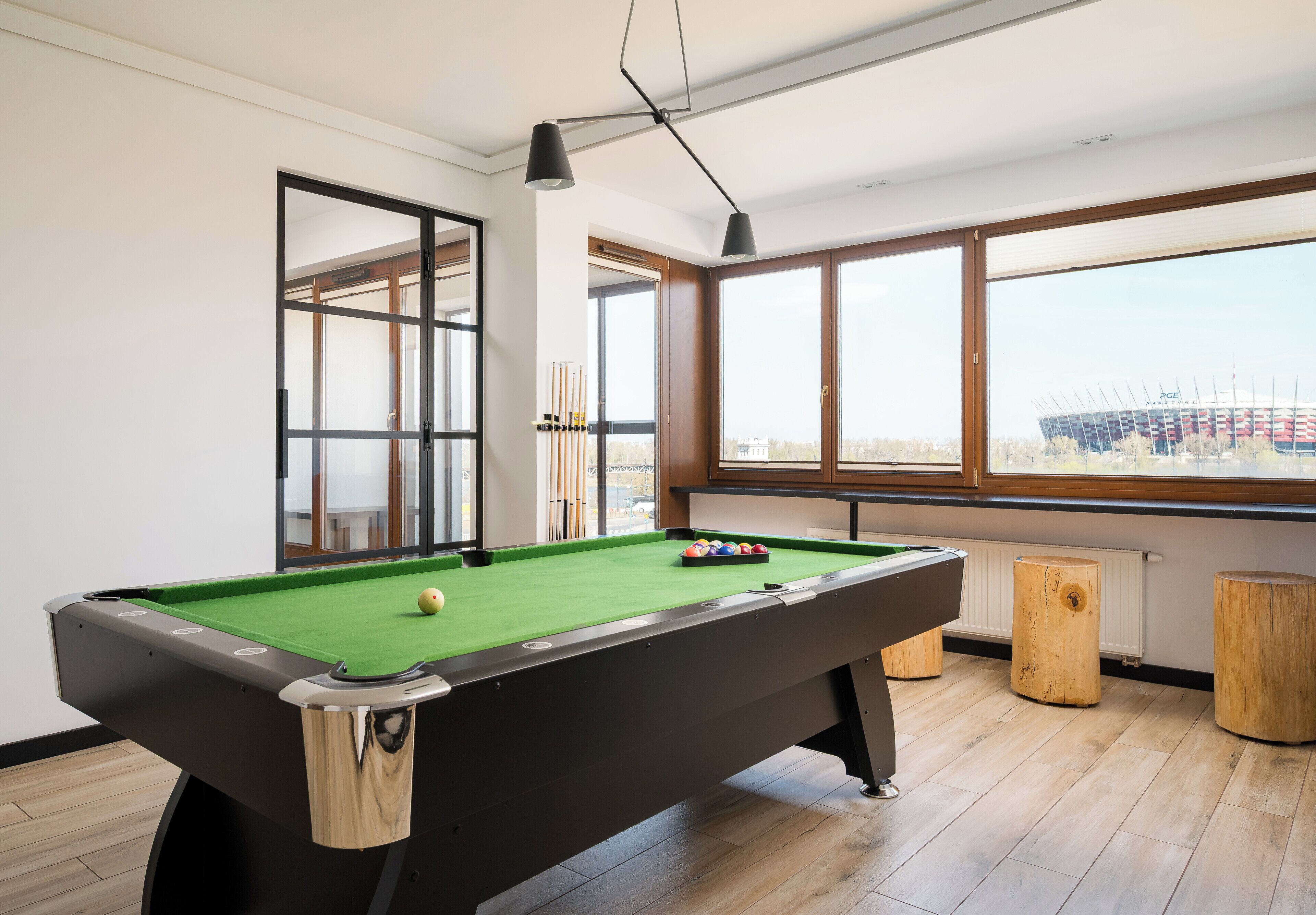 Une table de billard avec des billes, une fenêtre donnant sur un beau paysage et un plancher en bois.