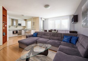 A modern living room with a sectional sofa, a glass coffee table, and a kitchen in the background. - Wola Kacza Spacious Apartment (Warszawa)