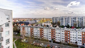 Ein Wohngebiet mit mehrstöckigen Wohngebäuden, einem Parkplatz und einem großen Industriegebäude im Hintergrund.