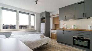 Ein modernes Hotelzimmer mit Bett, einer Küchenzeile, einem Fenster mit Stadtblick und einem Badezimmer.