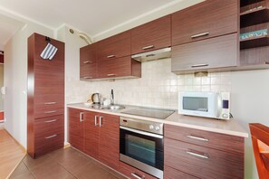 Een moderne keuken met houten kastjes, een inbouwoven, een magnetron en een roestvrijstalen spoelbak.