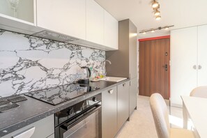 Una cocina moderna con salpicadero de mármol, electrodomésticos de acero inoxidable y una puerta de madera.
