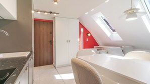Una cocina moderna con horno empotrado, un comedor con mesa y sillas blancas, y una pared de acento roja.