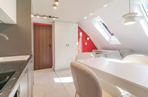 Una cocina moderna con horno empotrado, un comedor con mesa y sillas blancas, y una pared de acento roja.