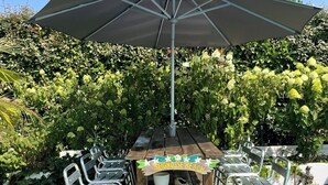 A wooden deck with metal chairs, a large umbrella, and a sign reading 'Seignosse Beach'. - Large air-conditioned family home with private, heated, secure swimming pool (Seignosse)