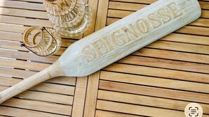 A wooden table with a white plaque engraved with 'SEIGNOSSE' and a wooden paddle. - Large air-conditioned family home with private, heated, secure swimming pool (Seignosse)