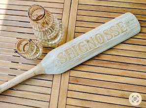 A wooden table with a white plaque engraved with 'SEIGNOSSE' and a wooden paddle. - Large air-conditioned family home with private, heated, secure swimming pool (Seignosse)